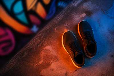 Tênis esportivo genérico sem marca sobre concreto urbano, grafite colorido desfocado ao fundo